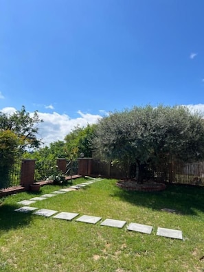 A backyard with a stone pathway leading to a wooden fence.
