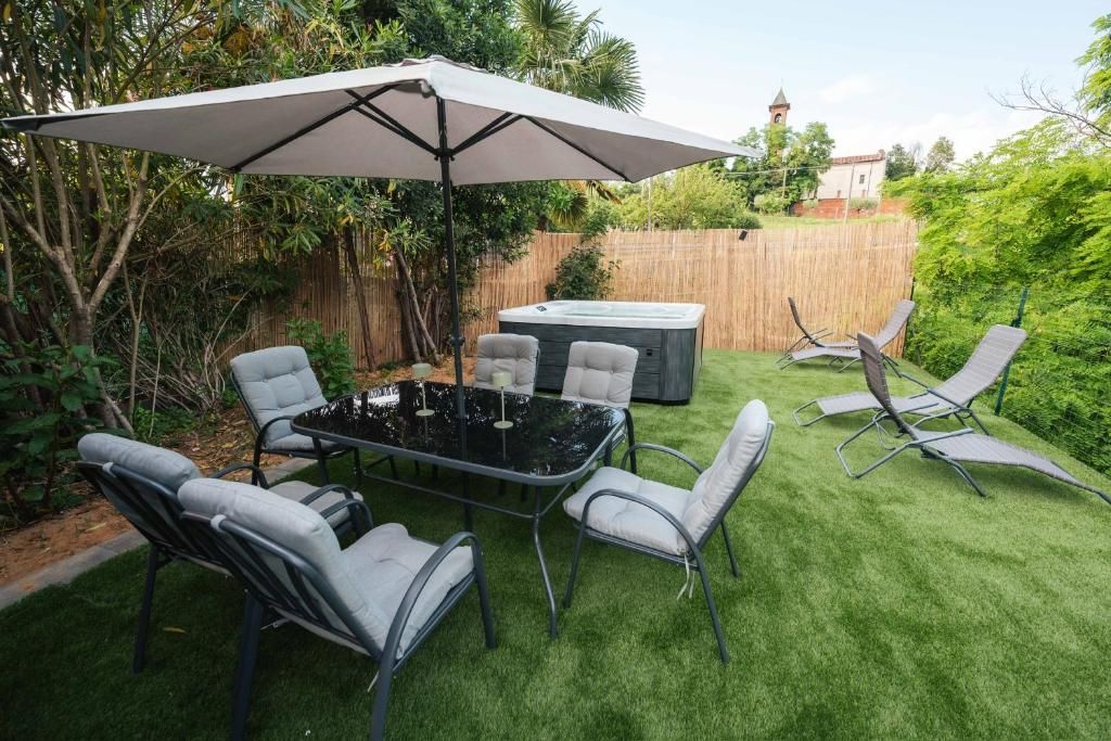 A backyard with a hot tub, a table with chairs, and a covered area.