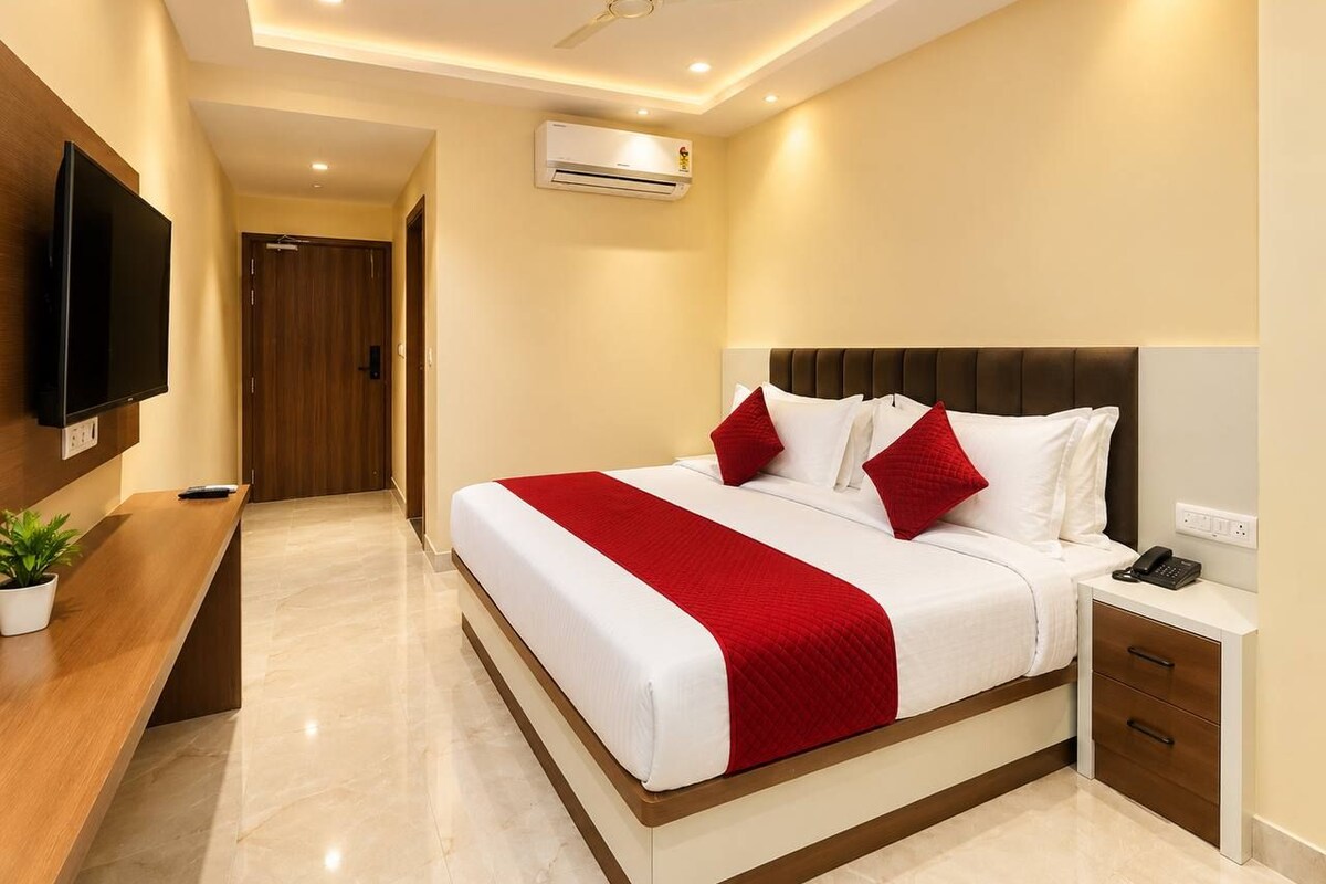 A hotel room with a bed, bedside table, TV, and a ceiling fan.