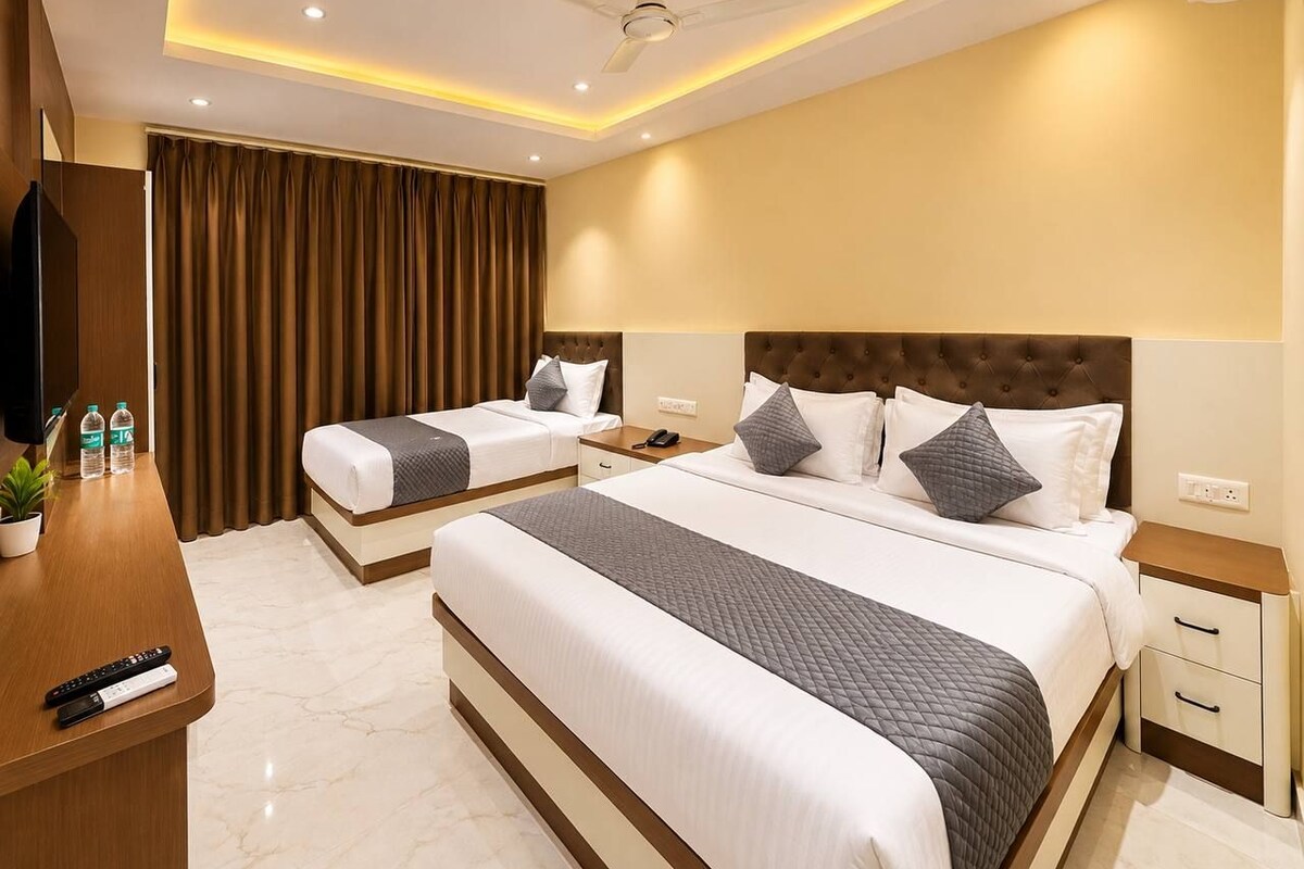 A hotel room with two beds, a desk, and a ceiling fan.