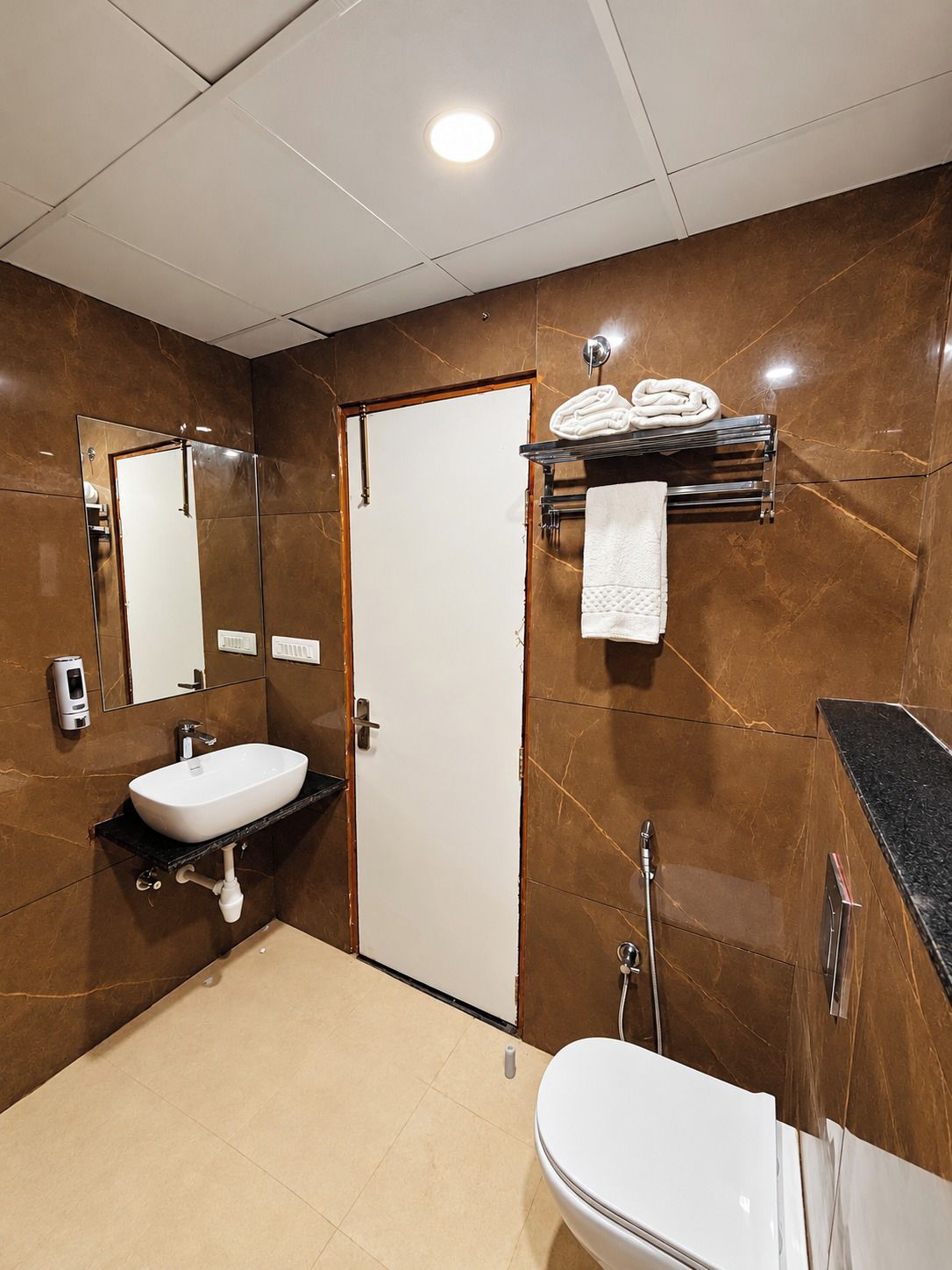 A modern bathroom with a white sink, a toilet, a mirror, and a towel rack.