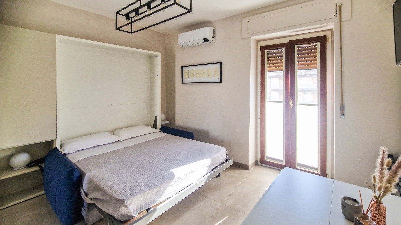 Une chambre à coucher avec un lit, une table de chevet et une fenêtre avec des stores.