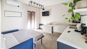 Una camera d'albergo con un letto, una scrivania, una macchina del caffè e una pianta.