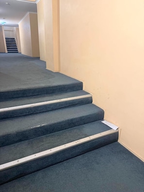 A carpeted staircase with a handrail and a landing area. - Spacious 3-Bedroom Stay in Central Wellington (Wellington)