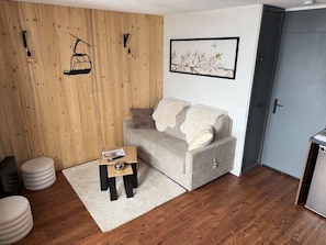 A cozy room with a grey sofa, a small wooden side table, and a white fluffy rug. - New Listing (Les Avanchers-Valmorel)