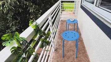 A balcony with a white railing, two blue tables, and green plants.