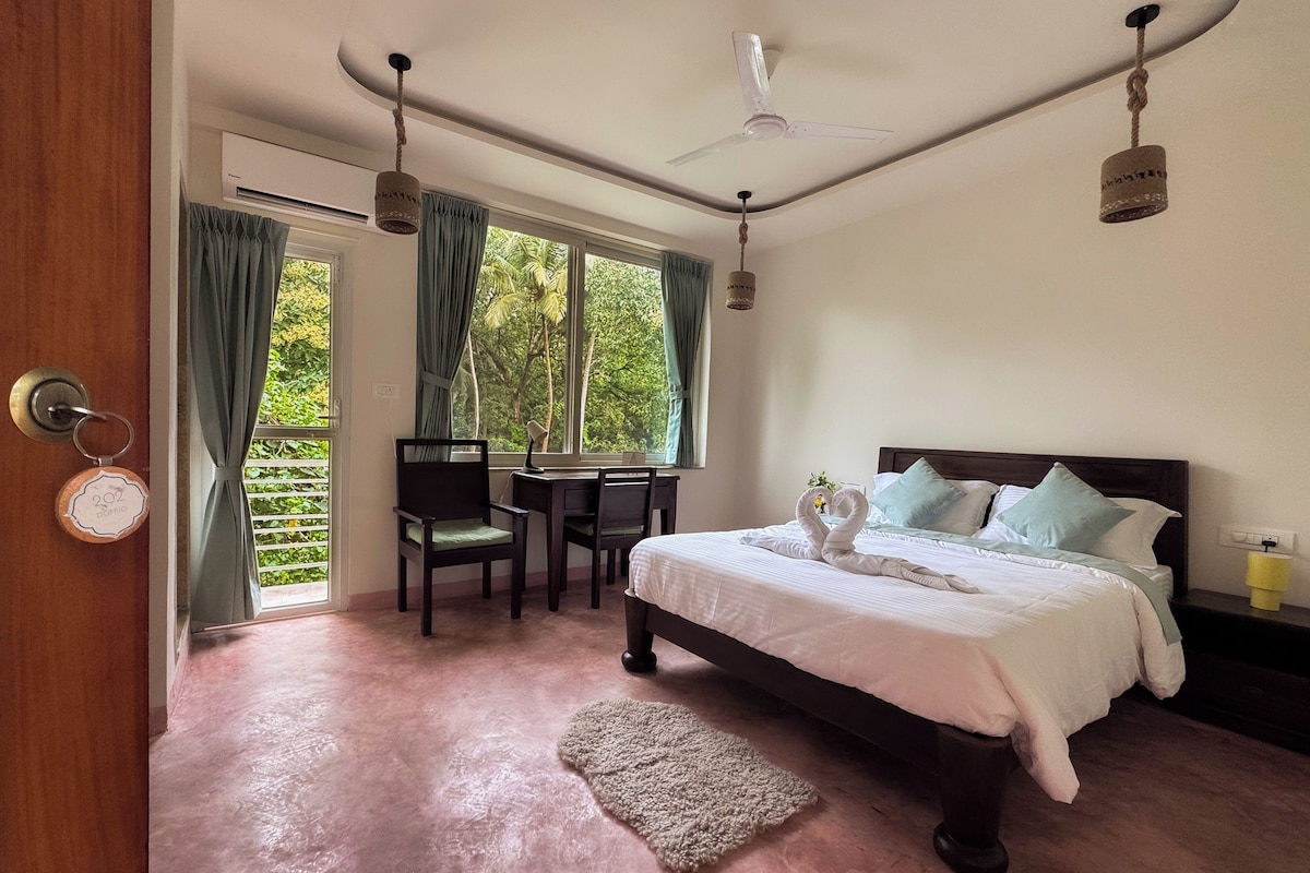 A bedroom with a bed, a desk, and a chair. There is a window with curtains, a ceiling fan, and a rug on the floor.