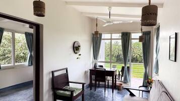 A room with a large window, a sofa, a dining table, and hanging lights.