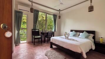 A bedroom with a bed, a desk, and a chair. There is a window with curtains, a ceiling fan, and a rug on the floor.