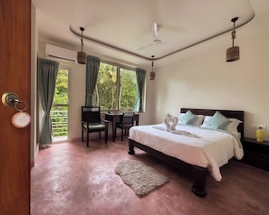 Un dormitorio con cama, escritorio y silla. Hay una ventana con cortinas, un ventilador de techo y una alfombra en el suelo.