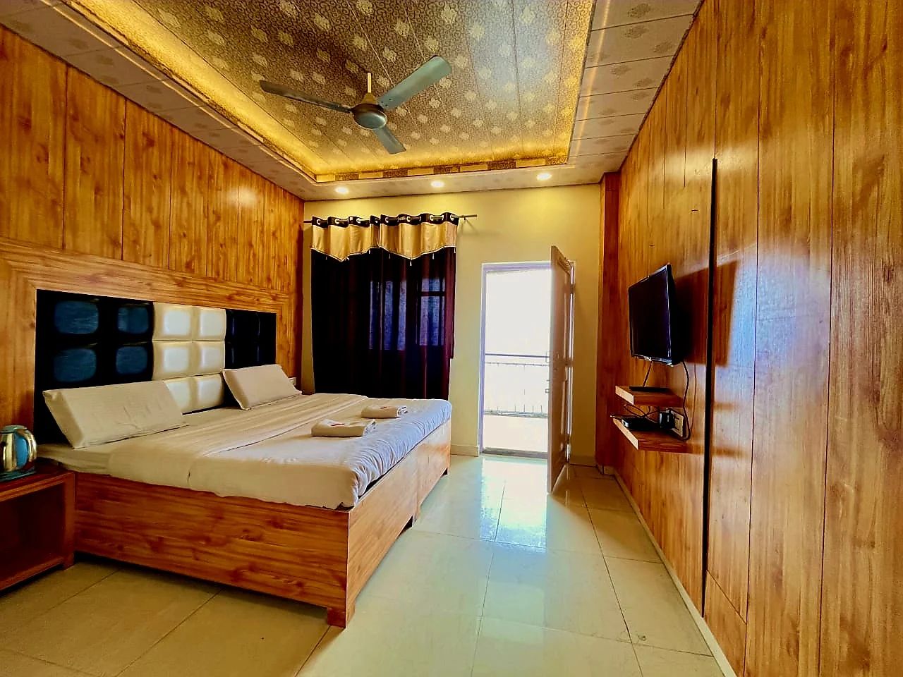 Un dormitorio con una cama de madera, una televisión y un ventilador de techo.