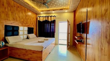 Un dormitorio con una cama de madera, una televisión y un ventilador de techo.