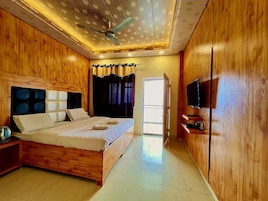 Une chambre à coucher avec un lit en bois, une télévision et un ventilateur de plafond.