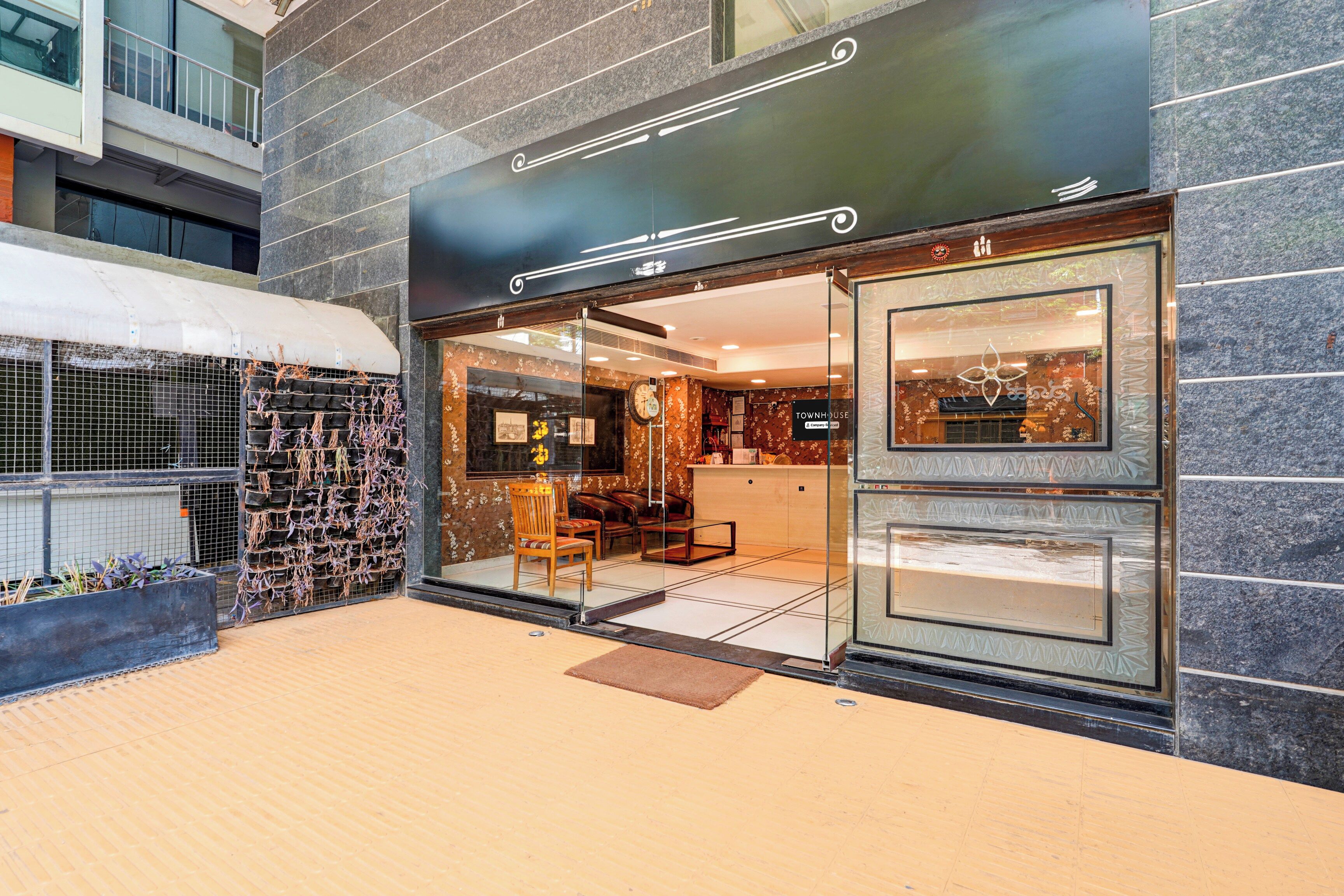 Un escaparate con diseño moderno, que incluye una entrada de vidrio, un área de descanso en el interior y una pared decorativa con un reloj.