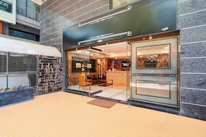Un escaparate con diseño moderno, que incluye una entrada de vidrio, un área de descanso en el interior y una pared decorativa con un reloj.
