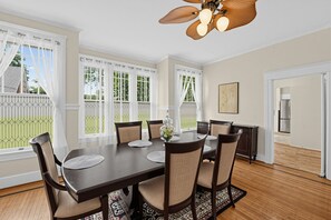 A dining room with a dark wooden table, beige upholstered chairs, and a decorative vase.
