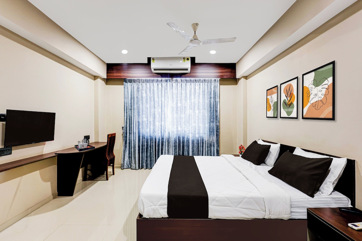 A hotel room with a bed, a desk, a television, and a ceiling fan.
