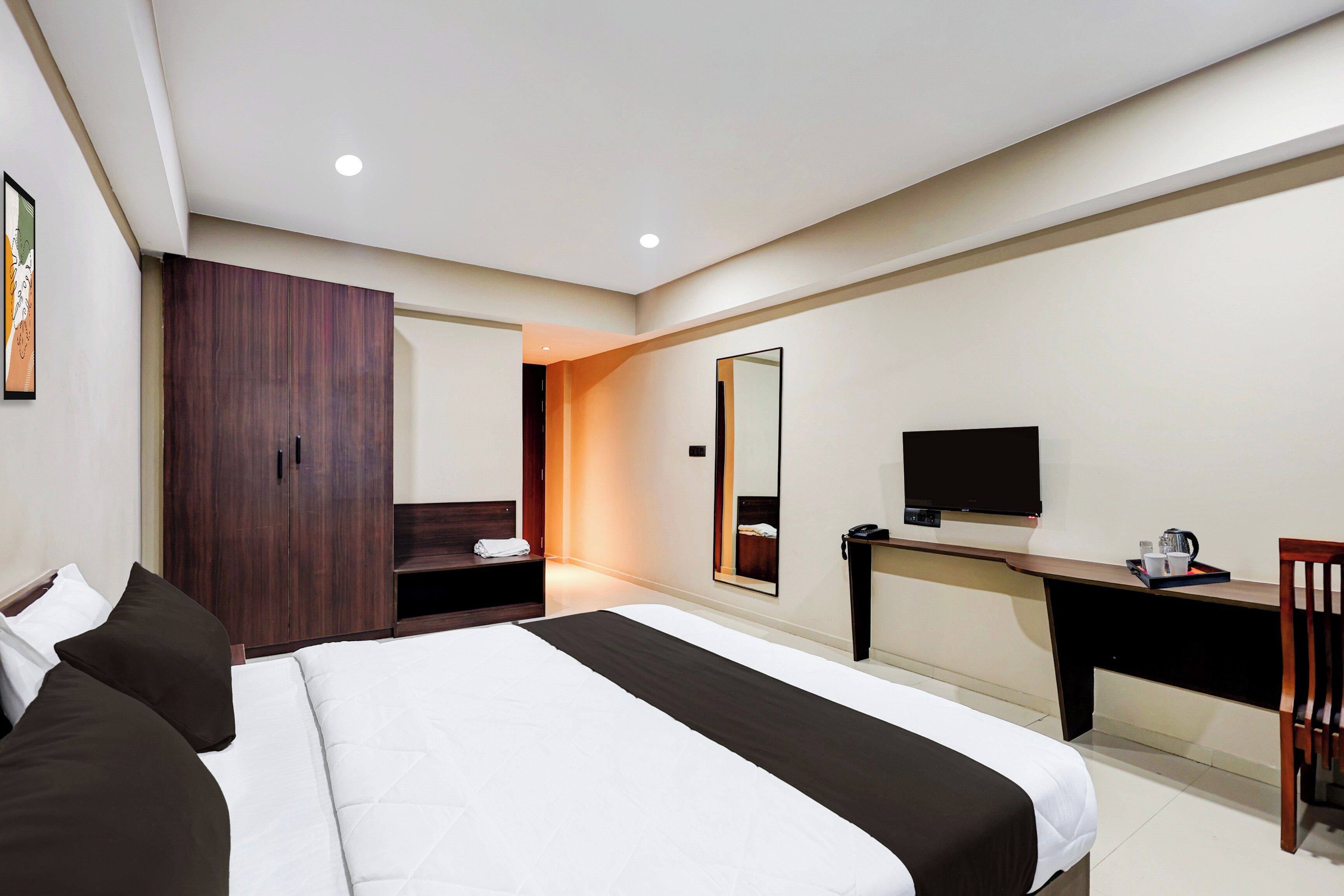 Una habitación de hotel con una cama, un escritorio, un televisor y un armario.