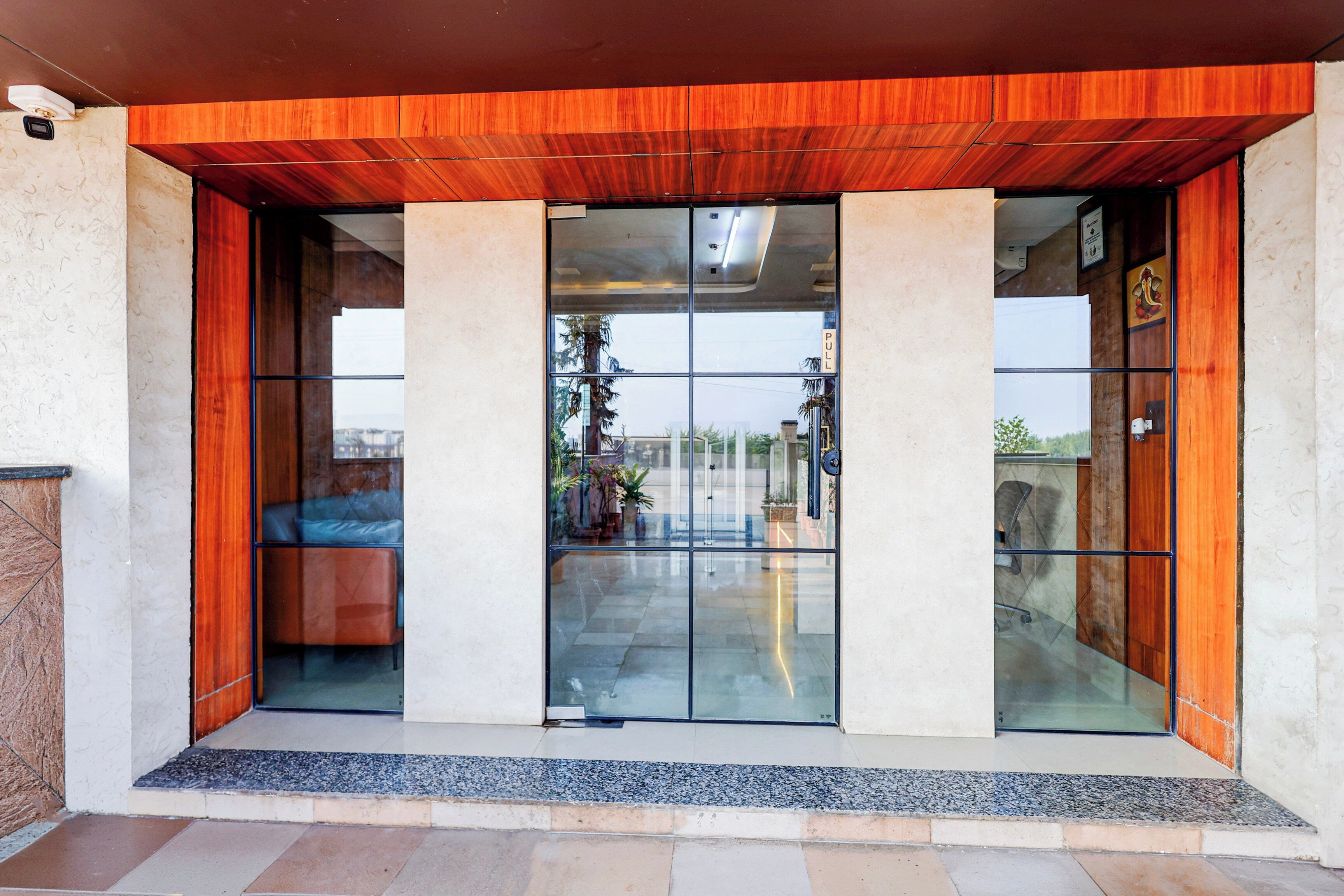 Una entrada de edificio moderna con puerta de cristal, techo de madera y pared de piedra.