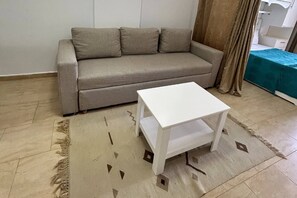 A living room with a sofa, a small white table, and a patterned rug. - Chalet With Side sea and Pool View, Turtles Beach (Hurghada)