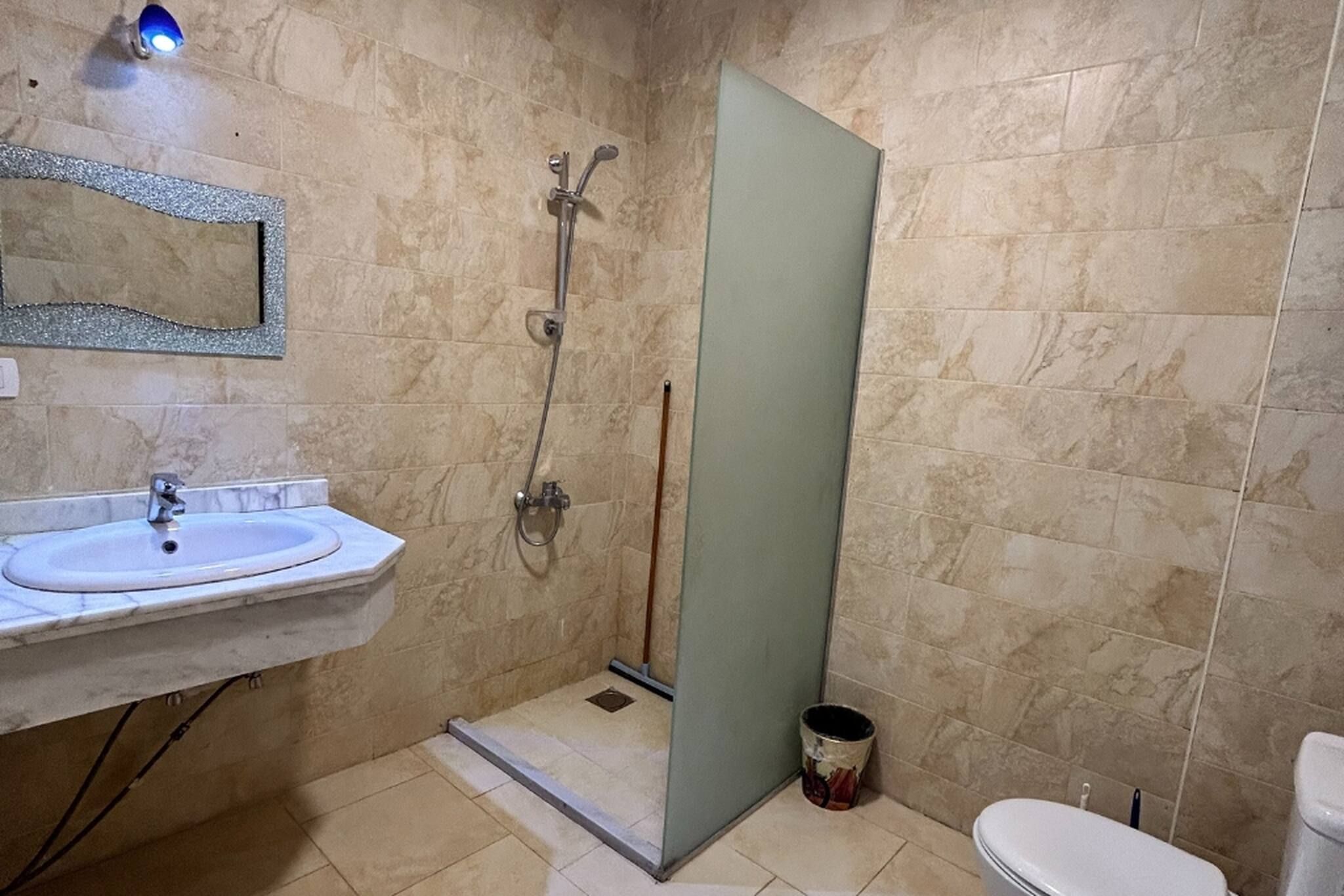 A bathroom with a sink, mirror, shower, and toilet.
