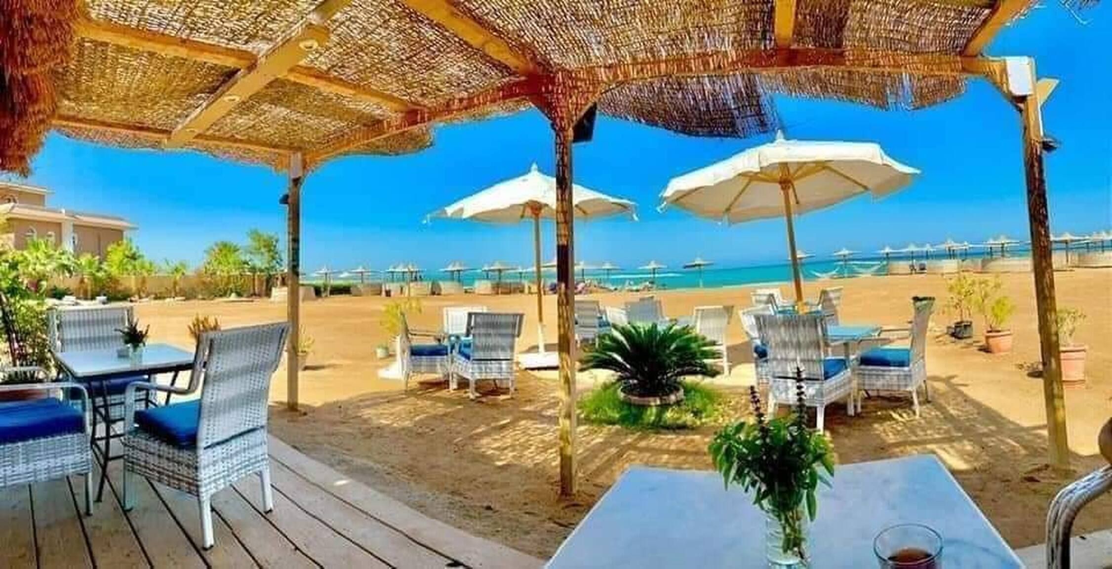 A beachside patio with outdoor seating and umbrellas, overlooking the ocean.