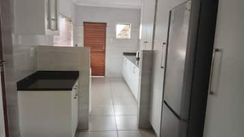 Una cocina con armarios blancos, un refrigerador de acero inoxidable y una encimera negra.