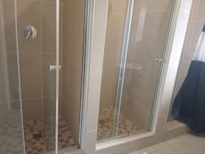A glass-enclosed shower area with tiled walls and a checkered floor pattern. - Spacious 5-bedroom House in Pietermaritzburg With Shared Pool (Pietermaritzburg)