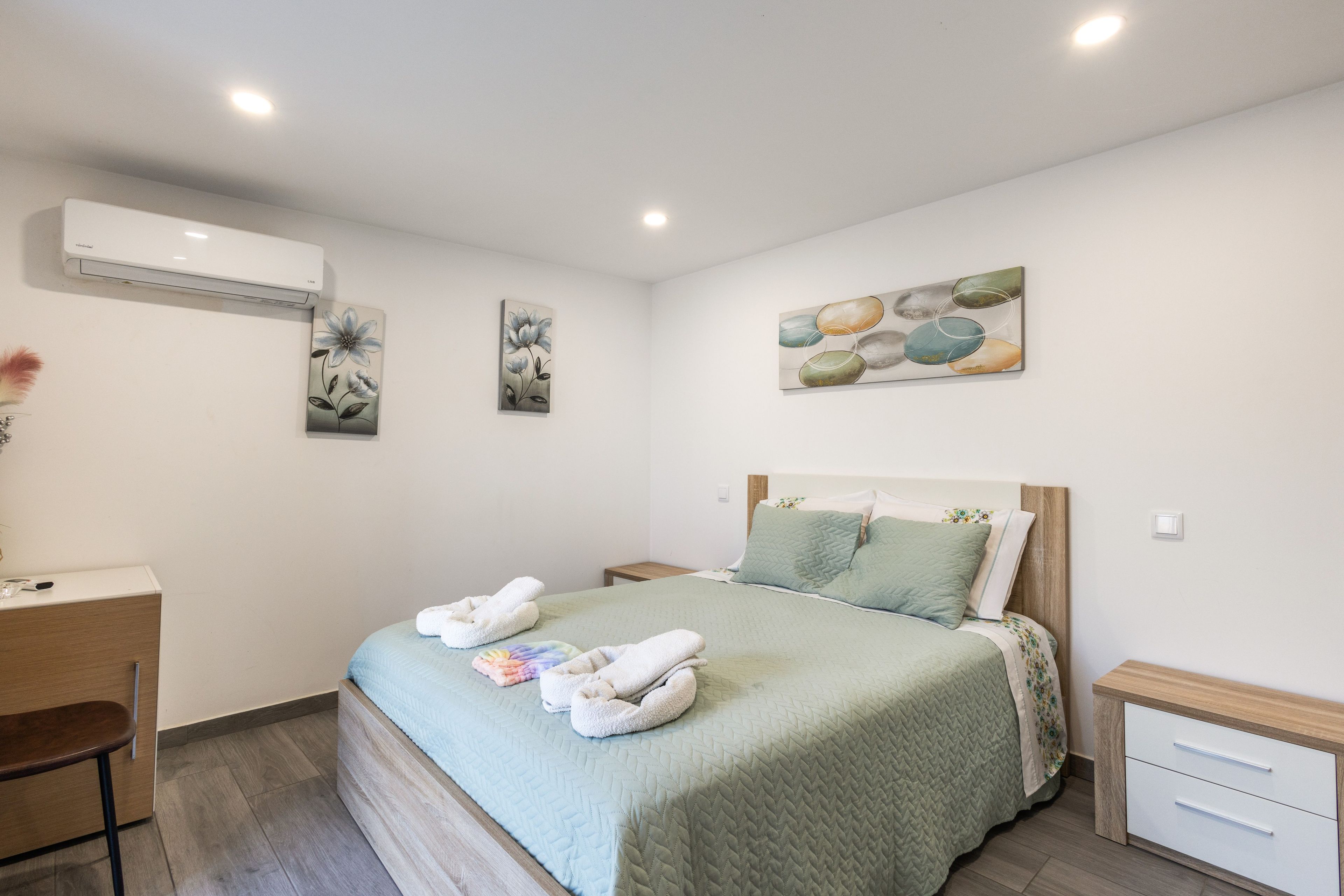 Une chambre à coucher comprenant un lit, des tables de chevet, un bureau et des œuvres d’art accrochées aux murs.
