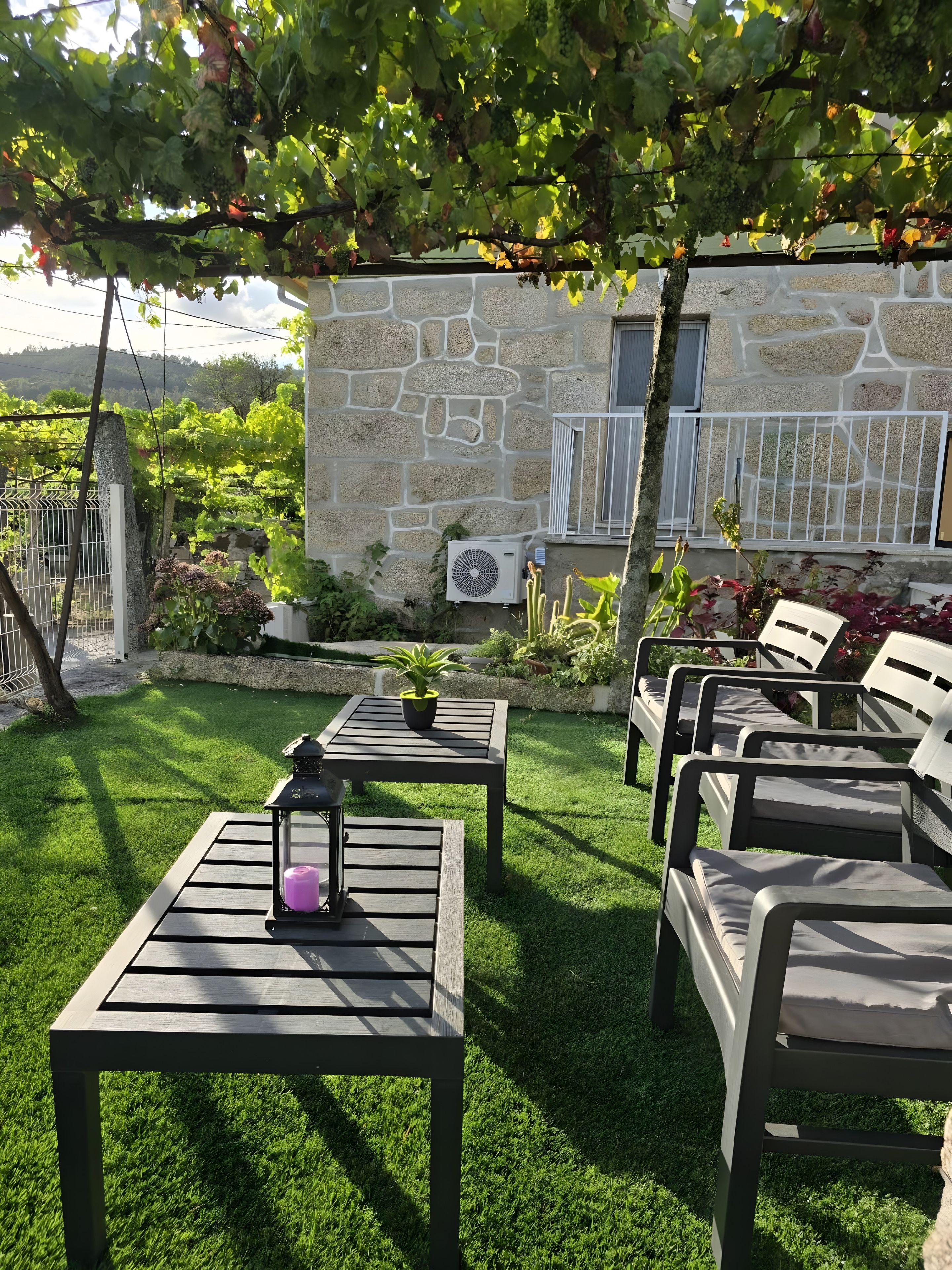 An outdoor seating area with tables and chairs, a stone wall, and a view of a vineyard.