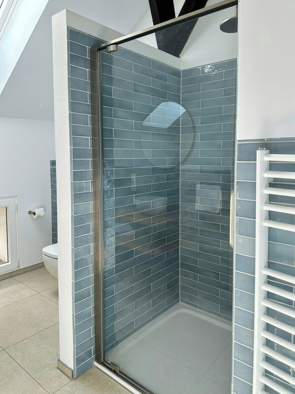 Een moderne badkamer met een douchecabine van glas, een toilet en een handdoekhouder.