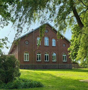 A large brick building with multiple arched windows and a symmetrical facade. - Historic apartment near the North Sea (Butjadingen)