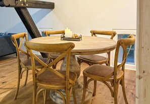A round wooden table with a candle and a tray of pinecones, surrounded by four wooden chairs with cushioned seats. - Historic apartment near the North Sea (Butjadingen)