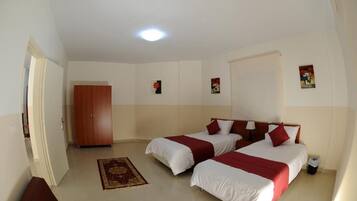 Quarto de hotel com duas camas, um guarda-roupa, um tapete pequeno e uma lixeira.