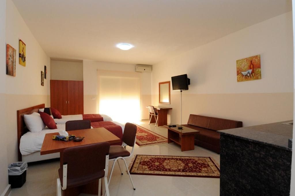 Habitación de hotel con cama, escritorio, silla, sofá, televisor y zona de cocina.