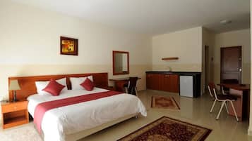 Habitación de hotel con cama, escritorio, kitchenette y baño pequeño.