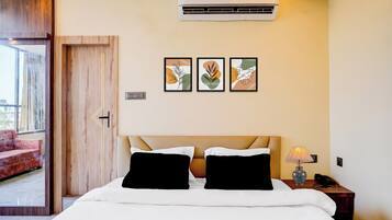 Ein Hotelzimmer mit Bett, Nachttisch, Lampe und Wandbildern.