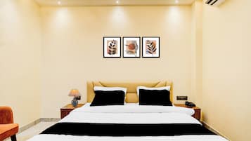 Une chambre d’hôtel avec un lit, des tables de chevet, une lampe, un téléphone et des œuvres d’art encadrées accrochées au mur.