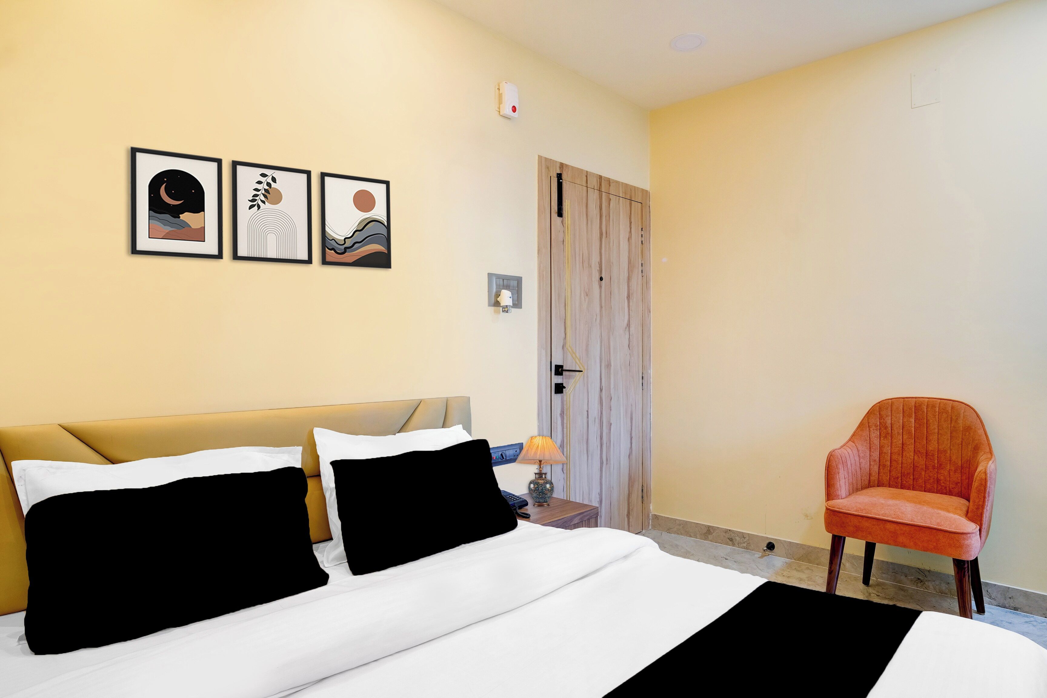 Habitació d'hotel amb un llit, una cadira i tres quadres al mur.