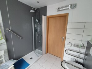 Une salle de bain moderne avec une douche à parois de verre, une porte en bois et un lavabo blanc doté d’un porte-serviettes.