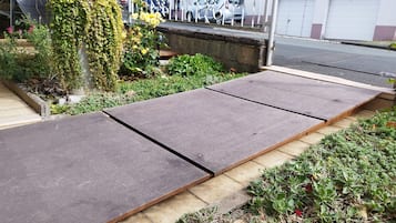 A garden area with a concrete pathway and a wooden bench.