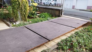 A garden area with a concrete pathway and a wooden bench.