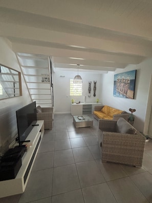 A living room with a TV, sofa, and a painting on the wall. - New Listing (Saint-François)