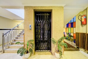 A hotel entrance with a metal gate, a staircase with metal railings, and potted plants. - Townhouse Godavarikhani Bus Terminal (Karimnagar)