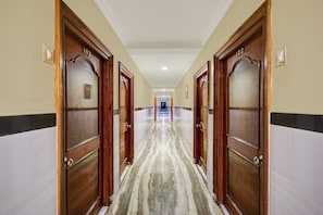 A hotel hallway with wooden doors numbered 103 and 122, marble flooring, and a white ceiling.