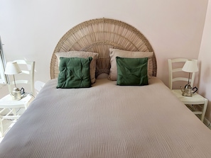 A bed with a woven headboard, two green pillows, and a white bedspread. - New Listing (Cabourg)