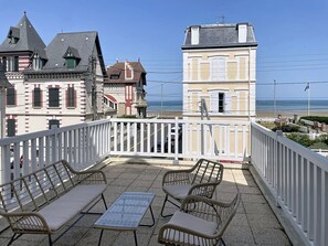 A balcony with wicker furniture and a view of the beach. - New Listing (Cabourg)