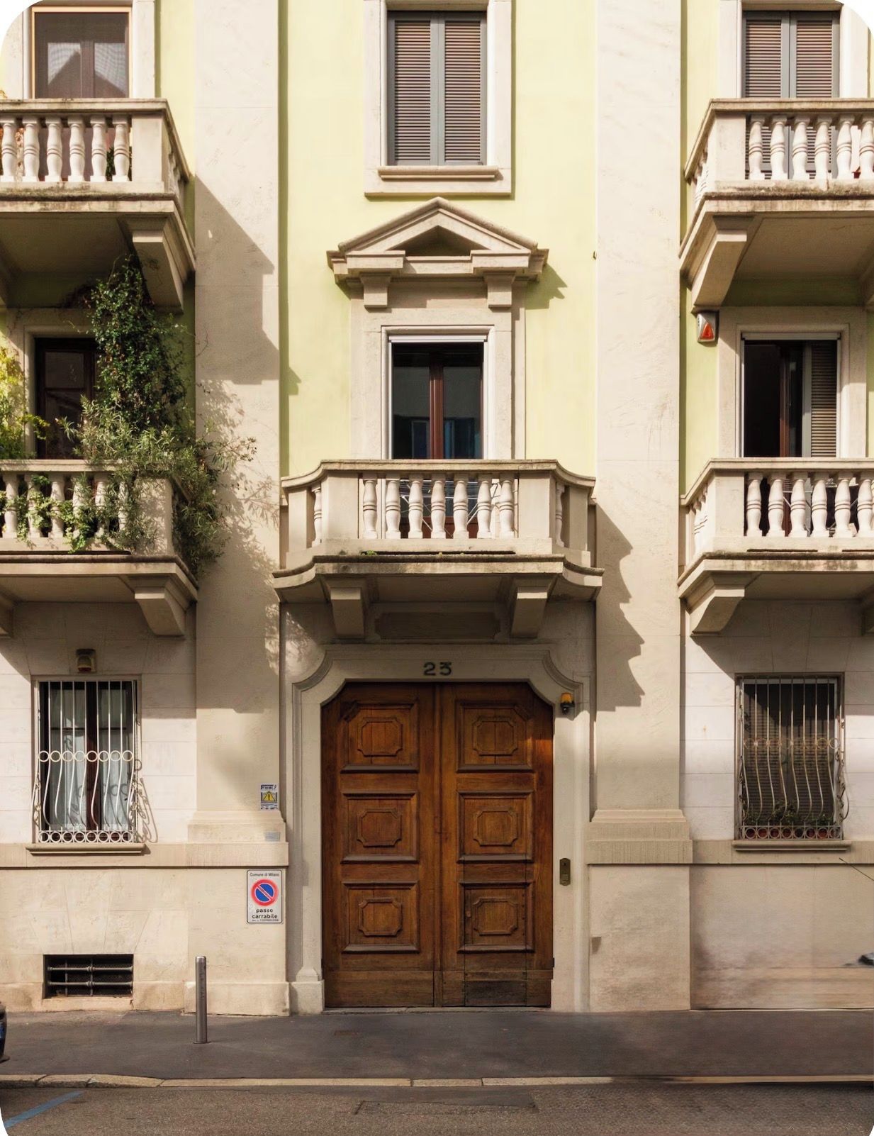 A building with a large wooden double door, a balcony with a balustrade, and a small window with metal bars.