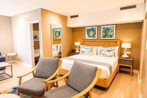 A hotel room with a bed, two armchairs, a bedside table with a lamp, and artwork on the wall. - Champagne Sports Resort (Central Drakensburg)