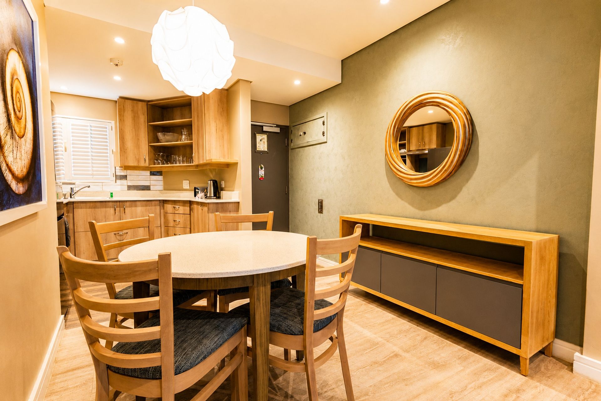 A modern kitchen with wooden cabinets, a round dining table, and a built-in bench.